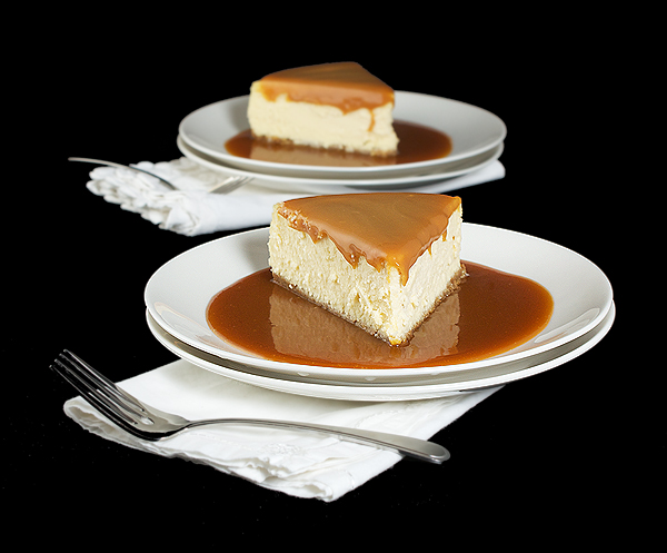 Amaretto Cheesecake with Almond Crust and Amaretto-Caramel Sauce A photo of 2 slices of Amaretto Cheesecake with Almond Crust in a pool of Amaretto-Caramel Sauce.