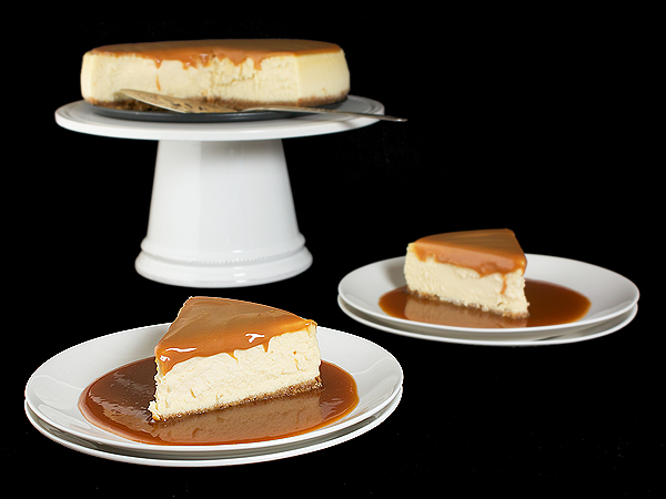 Cheesecakes A photo of an Amaretto Cheesecake on a cake stand with two slices displayed on dessert dishes in front.