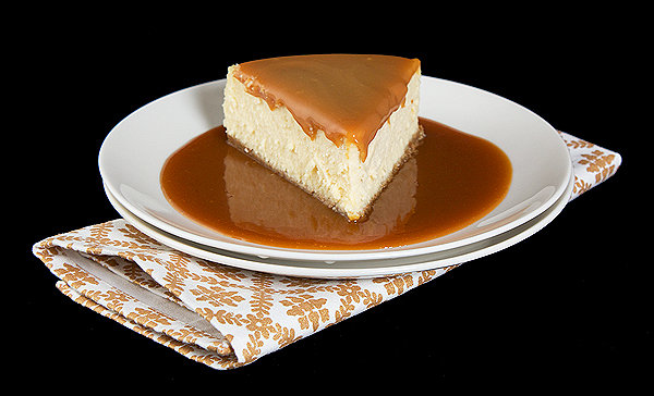 recipe caramel sauce, cheesecake crust, how to make cheesecake A photo of a slice of Amaretto Cheesecake set on a pool of Amaretto-Caramel Sauce.