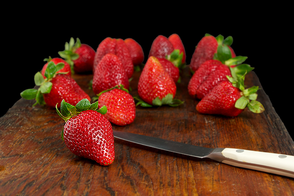 A photo of fresh strawberries displayed on a dark wooden board.