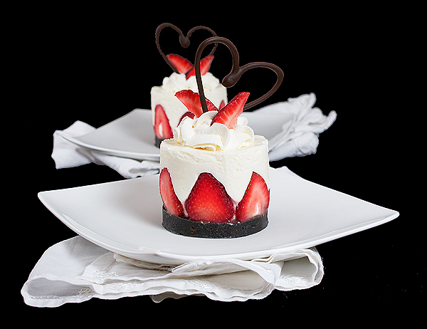 A photo of cold Yoghurt Cake, garnished with freshly whipped cream, strawberries and a chocolate heart.