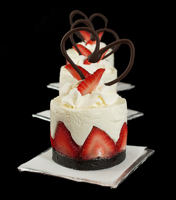 A photo of mini Italian Cakes with yogurt mousse, fresh strawberries and chocolate hearts.