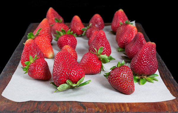 A photo of fresh strawberries displayed on a wooden board to be used in a Italian Dessert, Crostata di Fragole.