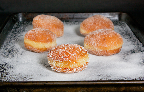 Bomboloni A photo of Italian Donuts, Bomboloni in a baking tray filled with sugar.