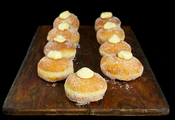 Krapfen A photo of Italian Donuts, Bomboloni also referred to as Krapfen displayed on a wooden board.