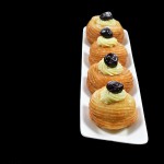 A photo of 4 Zeppole di San Giuseppe, St. Joseph's Day Fritters on a white rectangular dish set off to the side.