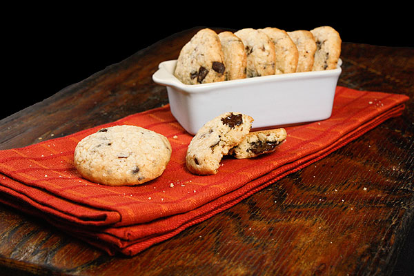 Grace's Sweet Life Chocolate Cookies A photo of chocolate and hazelnut cookies displayed on a red/orange cloth napkin with a jug of milk.