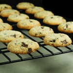 A cropped photo of Italian Cookies, hazelnut and chocolate chunk cookies, cooling on a black wire rack.