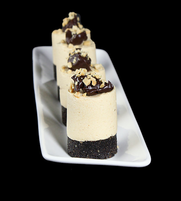Grace's Sweet Life Simple Cakes A photo of 4 Simple Cakes, Mini Chocolate Peanut Butter Mousse Cakes garnished with Fudge Sauce and chopped peanuts on a white rectangular-shaped dish.