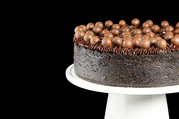 Grace's Sweet Life Simple Cheesecake A cropped photo of a Simple Cheesecake with Chocolate Ganache, Espresso Cheesecake Filling and Sour Cream topping garnished with chocolate ganache and chocolate whoppers.