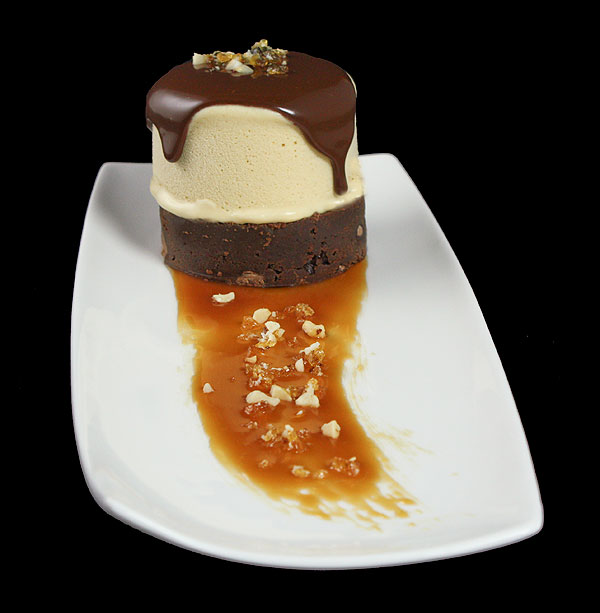 Grace's Sweet Life Salted Caramel Semifreddo A close up photo of Salted Caramel Semifreddo on a Triple Chocolate Fudge Brownie topped with Hot Chocolate Sauce and a sprinkling of Hazelnut Praline.