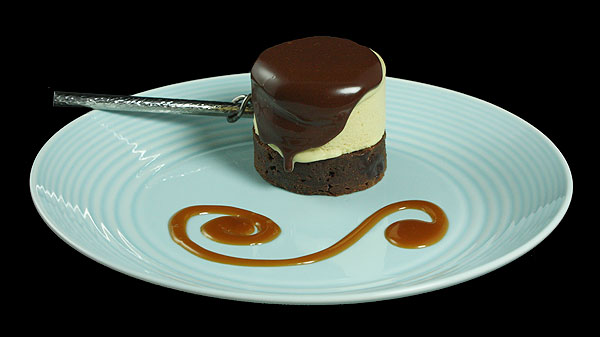Grace's Sweet Life Salted Caramel A photo of a Salted Caramel Semifreddo Cake with Chocolate Sauce on a blue dessert plate with a caramel swirl decorating the plate.