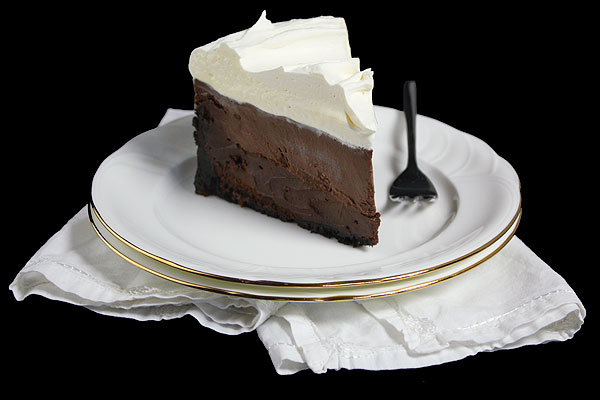 Mud Pie A photo of a slice of Mud Pie on a stack of 2 white dessert dishes with a white cloth napkin and a dessert fork.