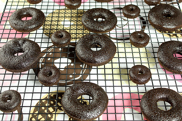 Chocolate Donuts from Grace's Sweet Life A photo taken looking down on mini and large chocolate cake donuts cooling on a wire rack.