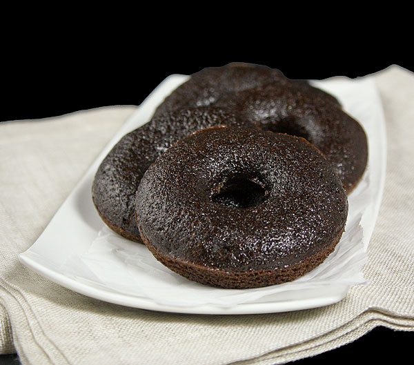 Grace's Sweet Life Baked Doughnuts A photo of dark chocolate Baked Doughnuts placed in a row on a rectangular shaped white dish.