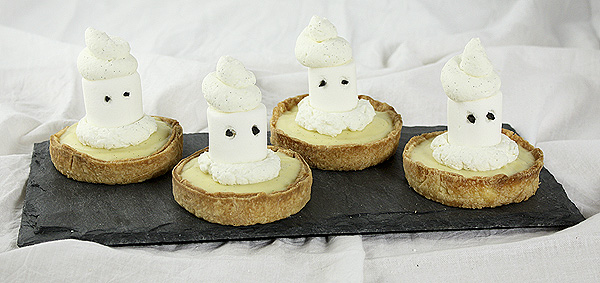 Four Marshmallow Ghost Tarts displayed side by side on a rectangle-shaped dark slate board.
