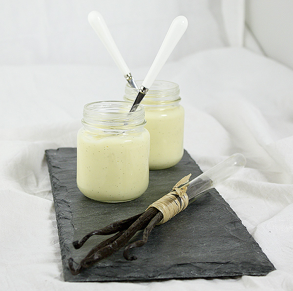 Vanilla Bean Pudding displayed with Vanilla Beans in glass tube on a slate board.