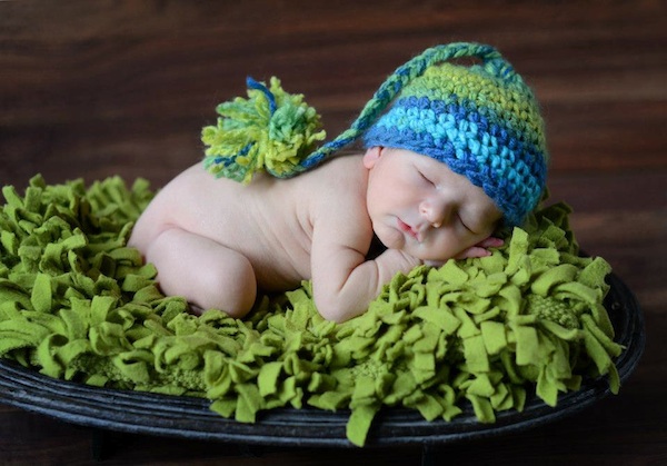 A photo of Grace's great-nephew, Grayson wearing nothing but a green and blue knitted toque on a green blanket.