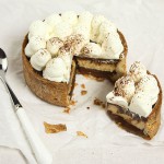 A photo taken looking down on a mini Caramel, Peanut Butter Mousse and Chocolate Tart that 's been cut with the slice set off slightly to the right displayed on baking paper with dessert spoon.