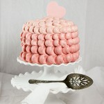 A photo of Pink Ombre Cake decorated with Pink Gum Paste Heart on white cake stand with antique cake server.
