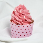 Close up photo of a Strawberry Cupcake with Pink Strawberry Frosting decorated with white sugar pearls in red dotted pink cupcake cup.