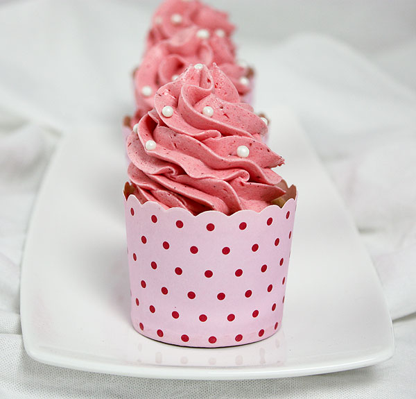 Close up photo of three Strawberry Cupcakes displayed in a row, one behind the other, on white rectangular shaped dessert platter.