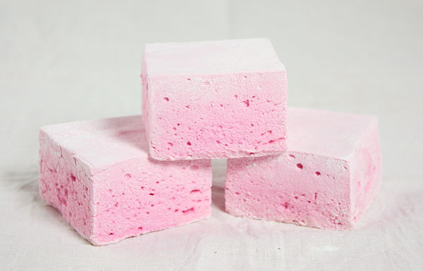 A close up photo of three Boozy Strawberry Marshmallows.