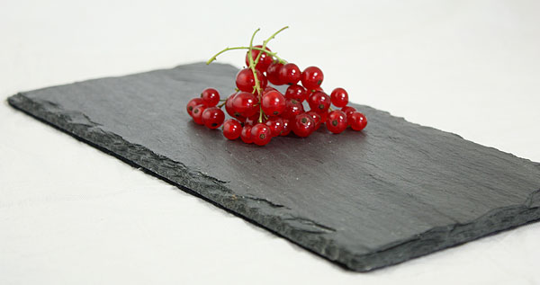 A photo of fresh red currants on black slate board.