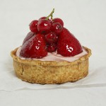 Close up photo of Strawberry Tart garnished with glazed fresh strawberries and red currants.