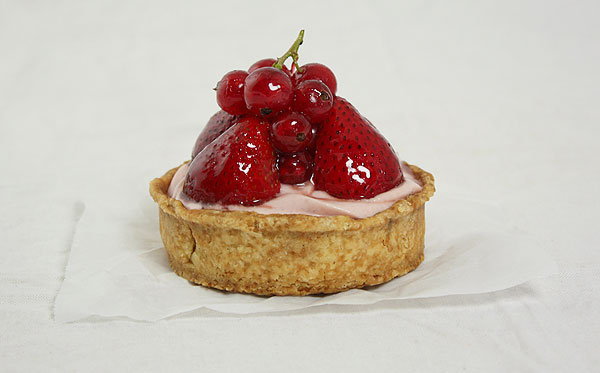 Close up photo of Strawberry Tart garnished with glazed fresh strawberries and red currants.