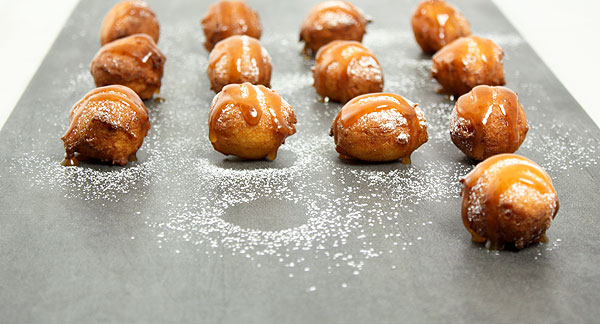 Close up photo of Ricotta Fritters displayed in rows on slate board.