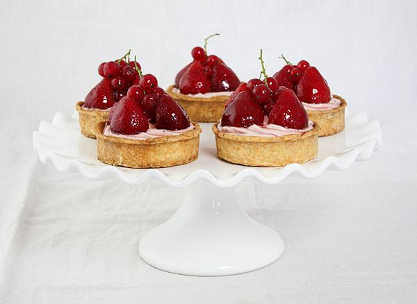Photo of Strawberry Cheesecake Tarts displayed on white cake stand.