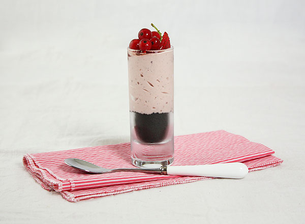 Close up photo of a Strawberry Cheesecake Verrine dessert displayed with dessert spoon on pink and white striped cloth napkin.