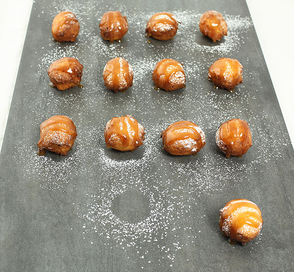 Photo taken looking down on Sweet Ricotta Fritters drizzled with Rum-Butter Caramel Sauce.