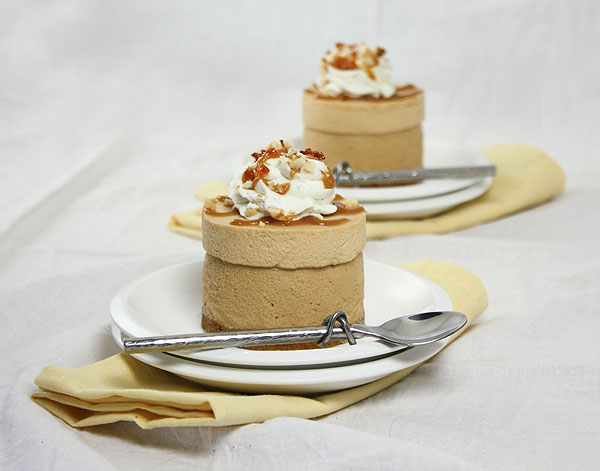 Photo of two Caramel Mousse mini cakes displayed on double stack white dessert dishes.