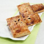 Blackberry Hand Pies displayed in a row on rectangle-shaped, white textured serving dish.