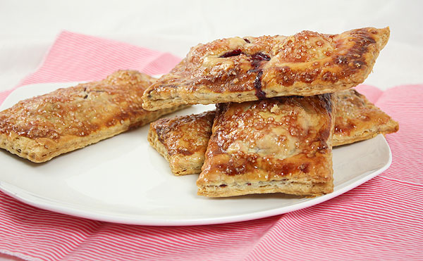 A photo of a stack of Blackberry Hand Pies on white dessert dish.