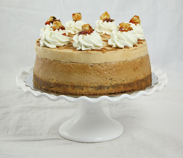 Close up photo of Caramel Mousse and Dulce de Leche Cheesecake Cake displayed on ruffled edge white cake stand.