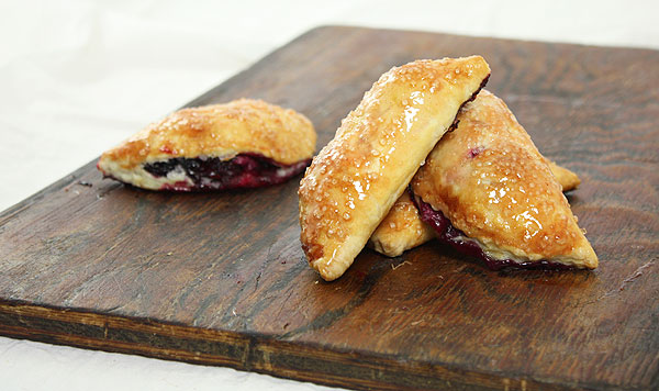 Photo of mini moon-shaped Hand Pies displayed on dark wooden board.