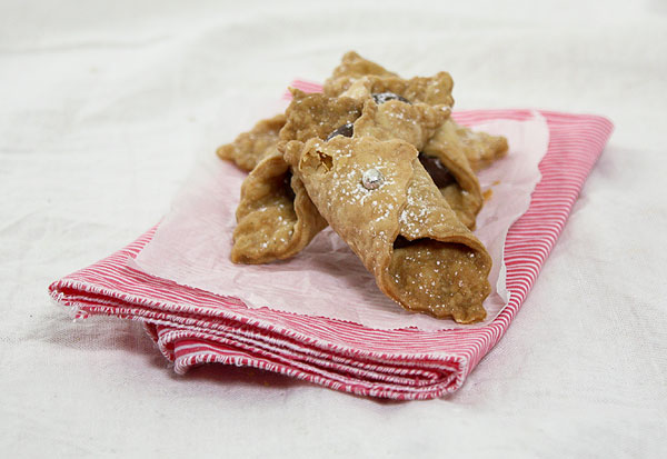 Close up photo of Italian Cookies with Nutella filling displayed on a pink and white cloth napkin lined with baking paper.