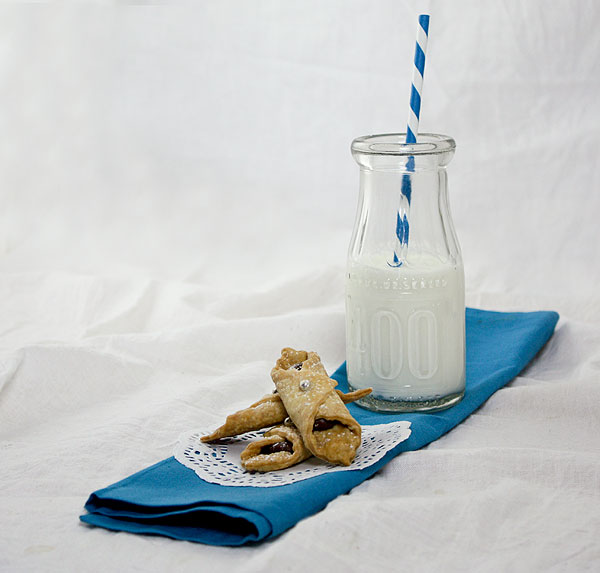 Photo of three Nutella Cookies (Farfallette con la Nutella) stacked on a white doilie with small jug of milk.